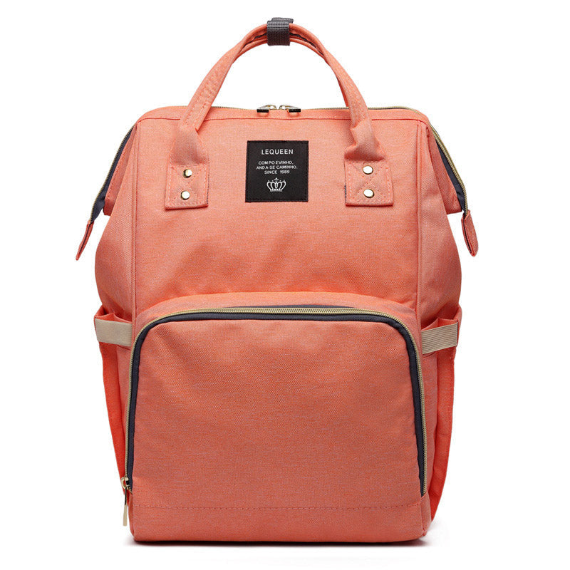 Maternity diaper bag in peach coral with front zipper pocket and black-trim interior section