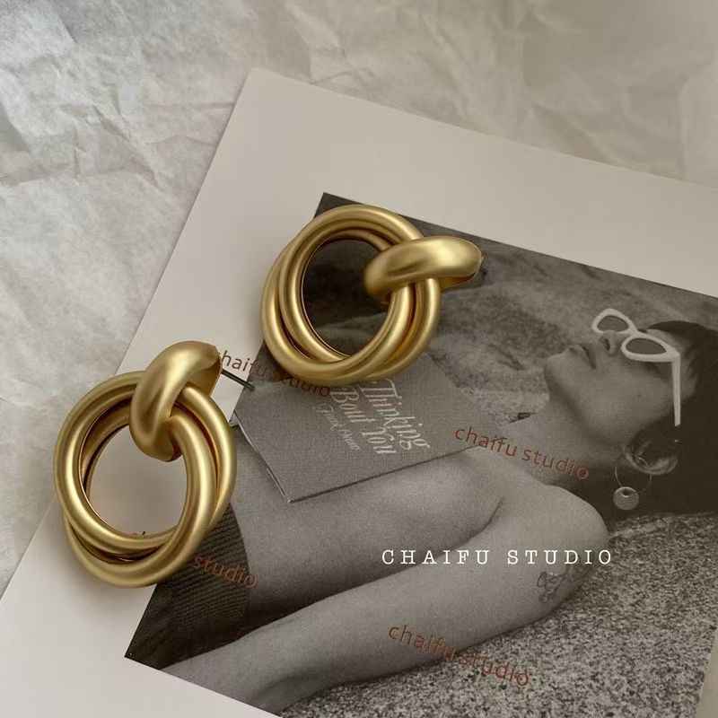 Gold statement earrings shown with two stacked circular metal loops