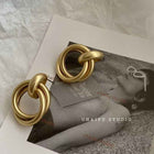 Gold statement earrings shown with two stacked circular metal loops