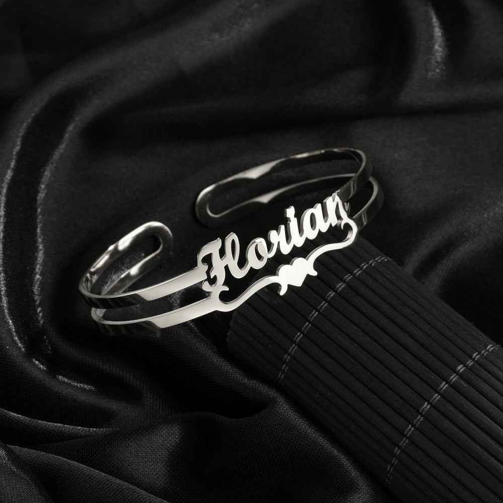 Silver personalized cuff bracelet with engraved cursive name, worn on wrist