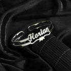 Silver personalized cuff bracelet with engraved cursive name, worn on wrist