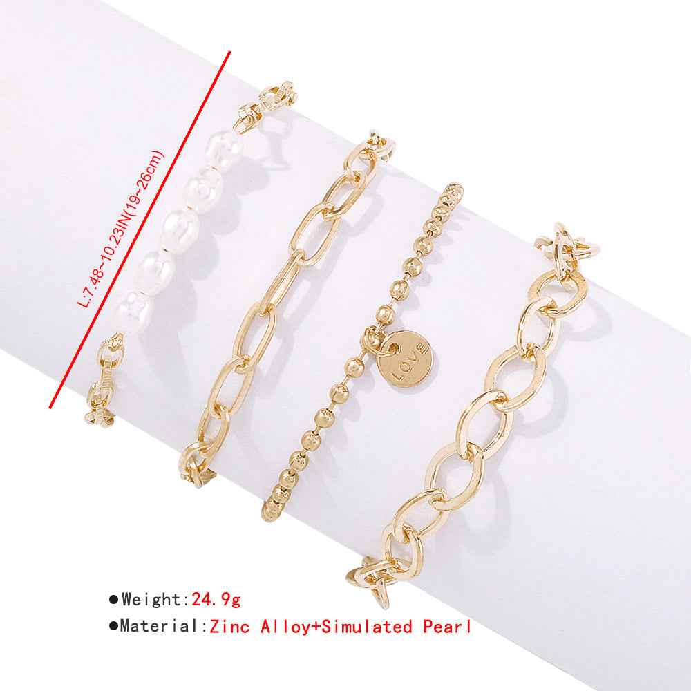 Gold-tone pearl bracelet set with oval links, bead chain, and small 'love' charm