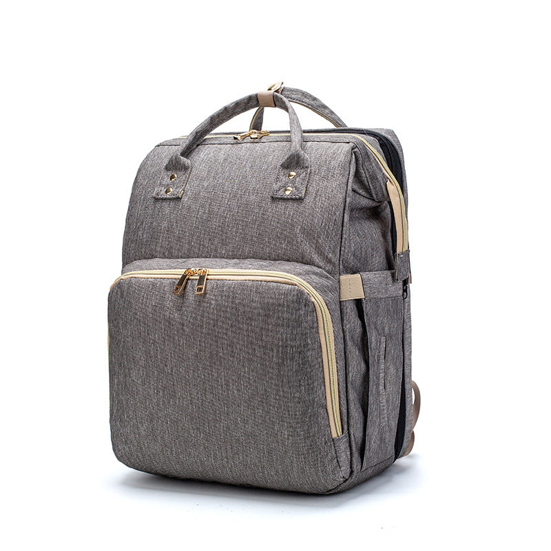Grey foldable baby travel bed backpack with top handle, front pocket, and side straps.