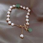 Pearl beaded bracelet with white freshwater pearls, green bead accents, and gold toggle clasp