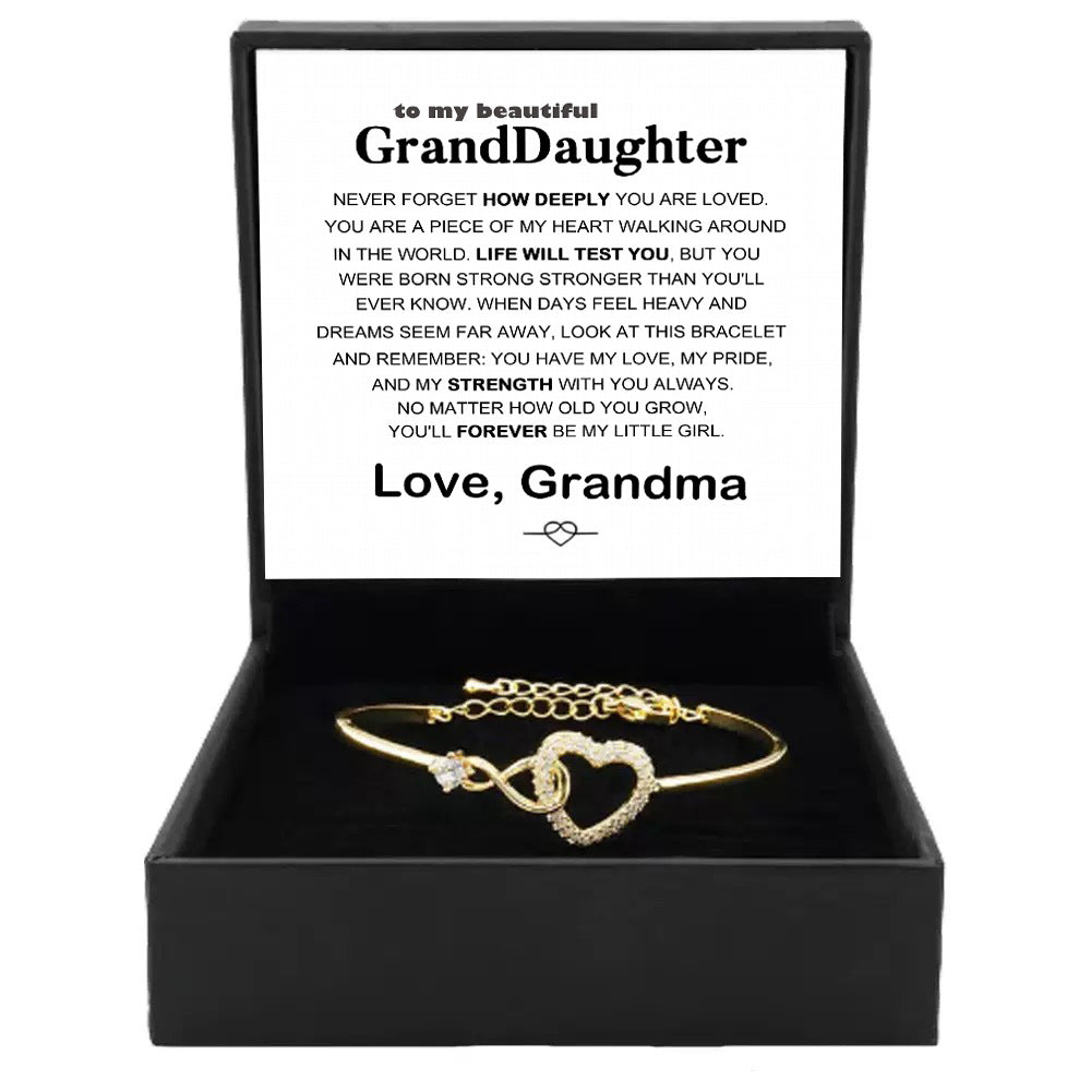 Gold open cuff bracelet with infinity-style heart charm and crystal-like stones