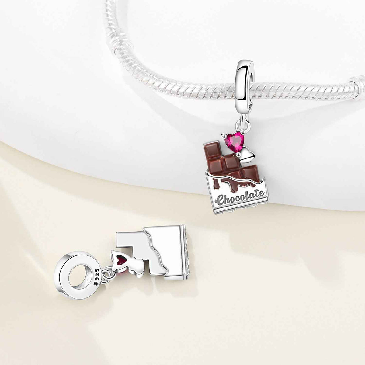 Chocolate-themed charm pendant with a pink heart gemstone on a silver bracelet
