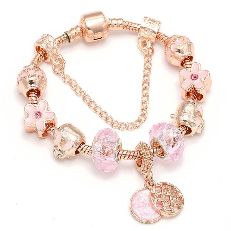 Rose gold charm bracelet with pink beads, flower and heart charms, and dangling coin pendant.