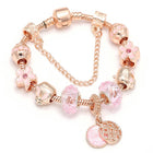 Rose gold charm bracelet with pink beads, flower and heart charms, and dangling coin pendant.