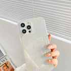 Cream transparent iPhone case with colorful heart pattern, close-up of hand holding