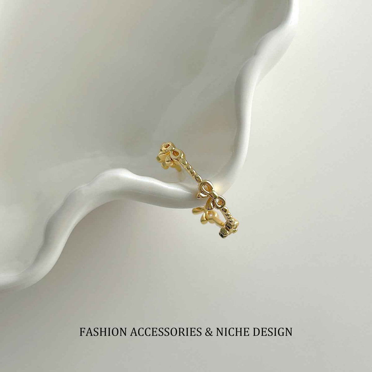 Gold-tone open bow link ring on stand, adjustable clasp and chain detail