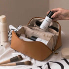 Tan travel cosmetic bag opened with zip top, inner divider pockets visible