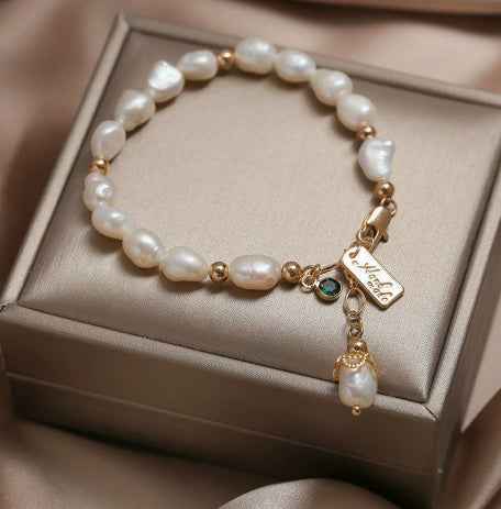 Gold-tone pearl bracelet featuring zircon centerpiece and hanging pearl charm