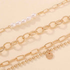 Close-up gold-tone chain bracelet with oval links, pearl beads, and 'love' charm