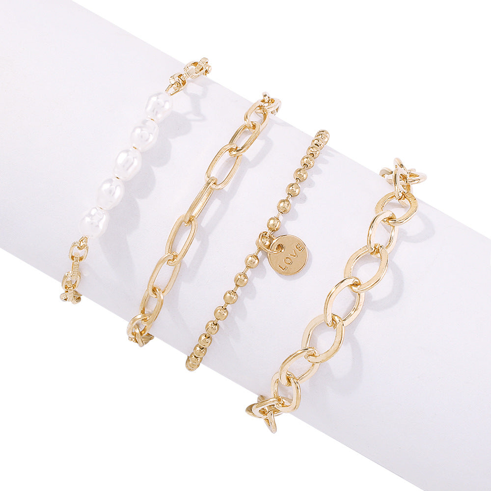 Gold-tone pearl bracelet set with oval links and bead chain charms