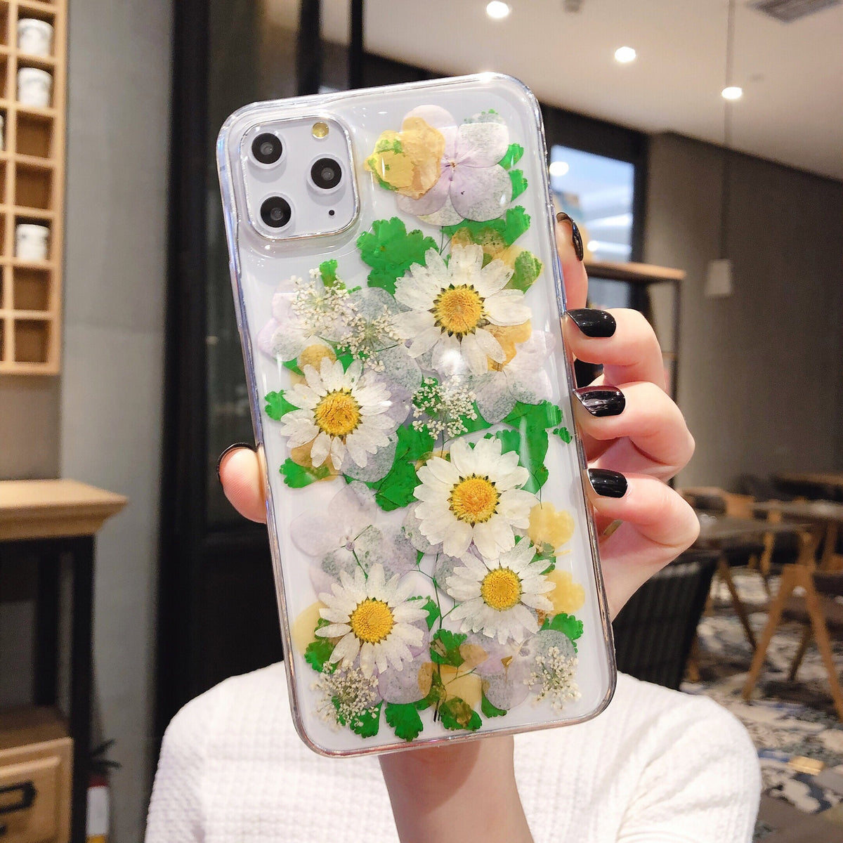 Clear iPhone case with preserved green leaves and white daisies with yellow centers