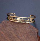 Gold stainless steel cuff bracelet with engraved cursive text and heart-shaped cutout ends
