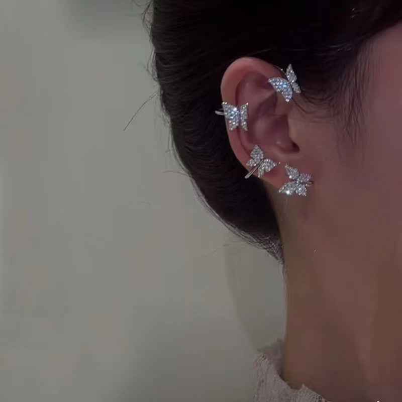 Silver butterfly earrings on the ear, featuring a hoop frame and multiple butterfly shapes