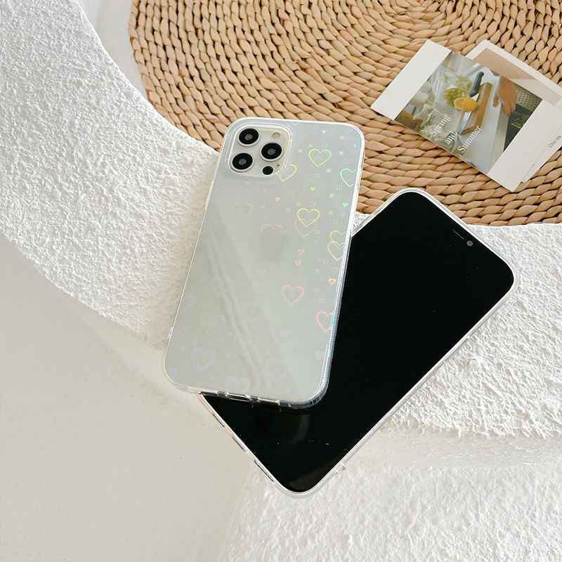 Transparent cream iPhone case with rainbow hearts, shown next to black phone screen