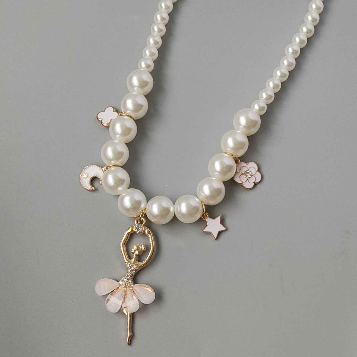 Pink pearl necklace with heart, star, and floral charms on a gold-tone chain