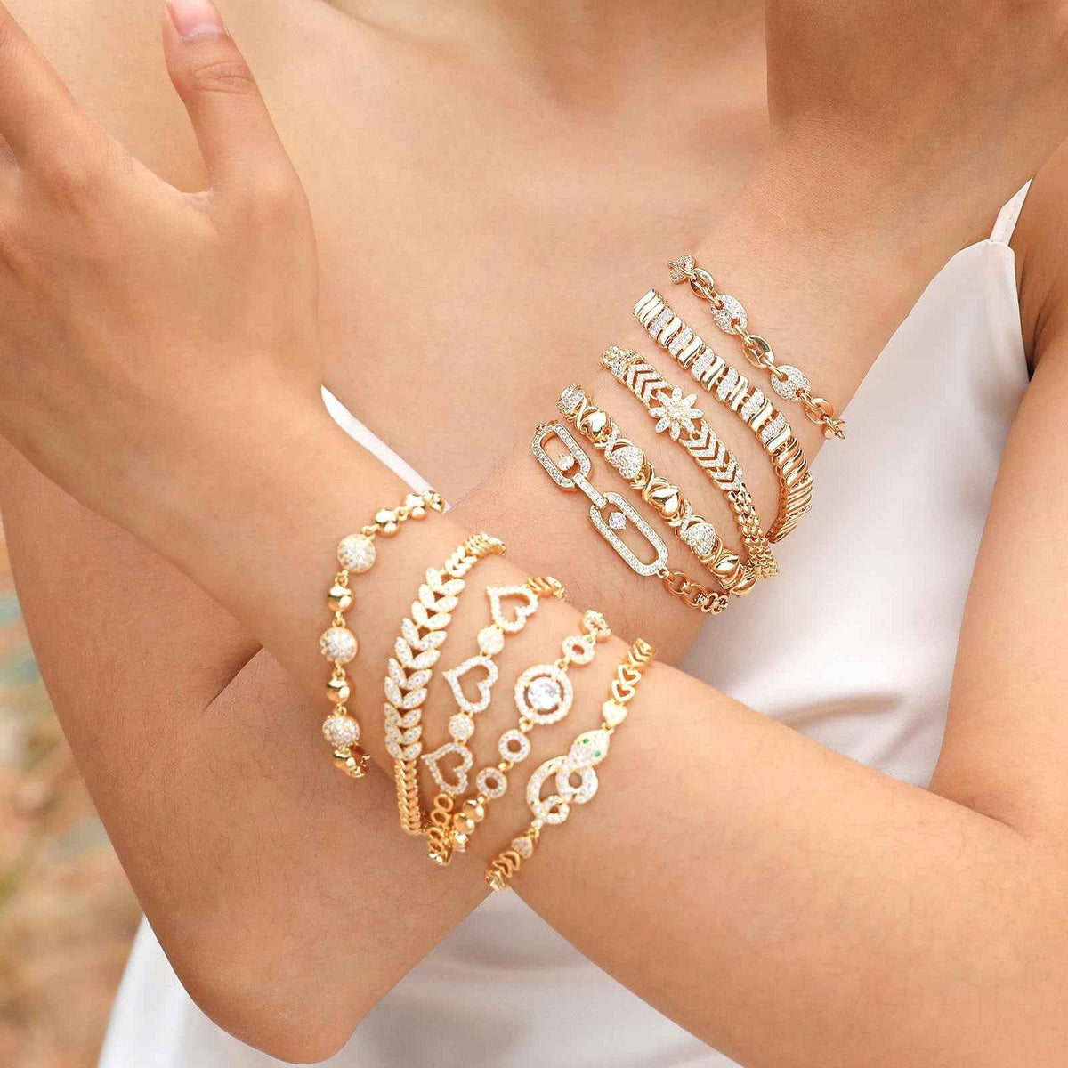 Gold-tone crystal bracelet with heart and flower charms, worn on wrist