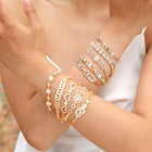 Gold-tone crystal bracelet with heart and flower charms, worn on wrist