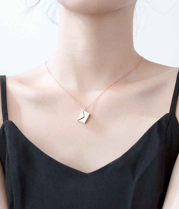 Rose gold envelope pendant necklace worn on a model’s neck