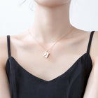 Rose gold envelope pendant necklace worn on a model’s neck