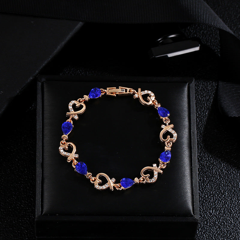 Rhinestone heart charm bracelet with deep blue stones and heart links in rose-gold tone