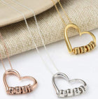 Heart pendant name necklace with mixed metal charms and chain links, close-up view