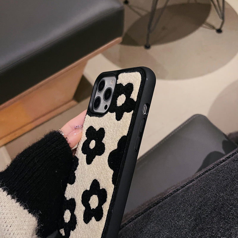 Plush floral iPhone case with cream-and-black flower design; raised camera cutout, side buttons