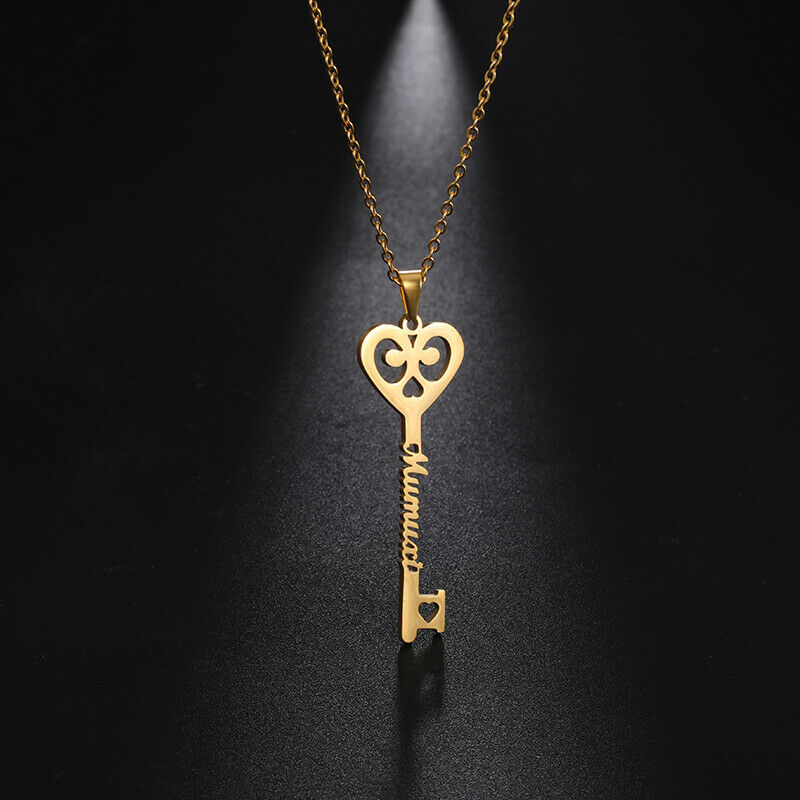 Close-up gold key pendant necklace with heart-shaped charm and engraved cursive name