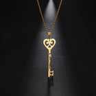 Close-up gold key pendant necklace with heart-shaped charm and engraved cursive name