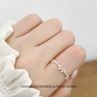 Silver-tone open bow link ring on hand, adjustable fit with chain detail