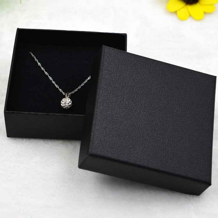 Silver-tone pendant chain with round stone, shown inside a black jewelry box