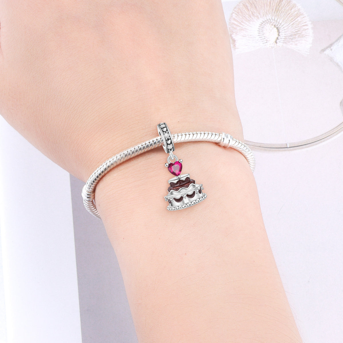 Silver-tone charm bracelet with pink heart and crown-style centerpiece