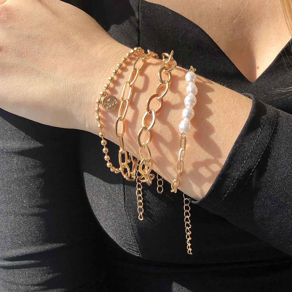 Stack of gold-tone pearl chain bracelets with coin charms and long drop dangles