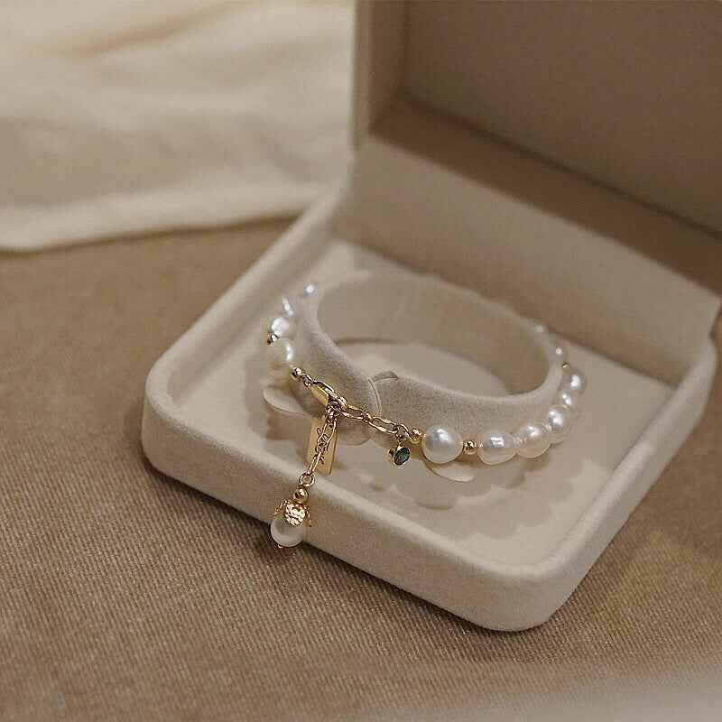 Gold pearl bracelet in box with layered links, tag charm, and dangling pearl