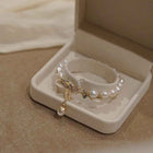 Gold pearl bracelet in box with layered links, tag charm, and dangling pearl