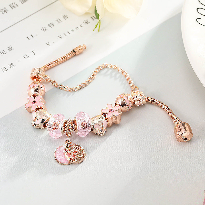 Rose gold bracelet with pink crystal beads and round medallion charm with heart detail.