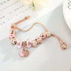 Rose gold bracelet with pink crystal beads and round medallion charm with heart detail.