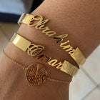 Gold personalized cuff bracelet with engraved cursive name, worn on wrist