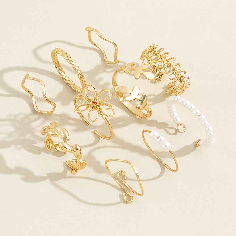 Gold-tone openwork flower rings with pearl accents, shown in flat lay