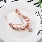 Rose gold bracelet with pink crystal beads and small heart charm dangle on the chain.