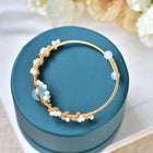 Gold braided pearl cuff bracelet with white beads and light blue round accents